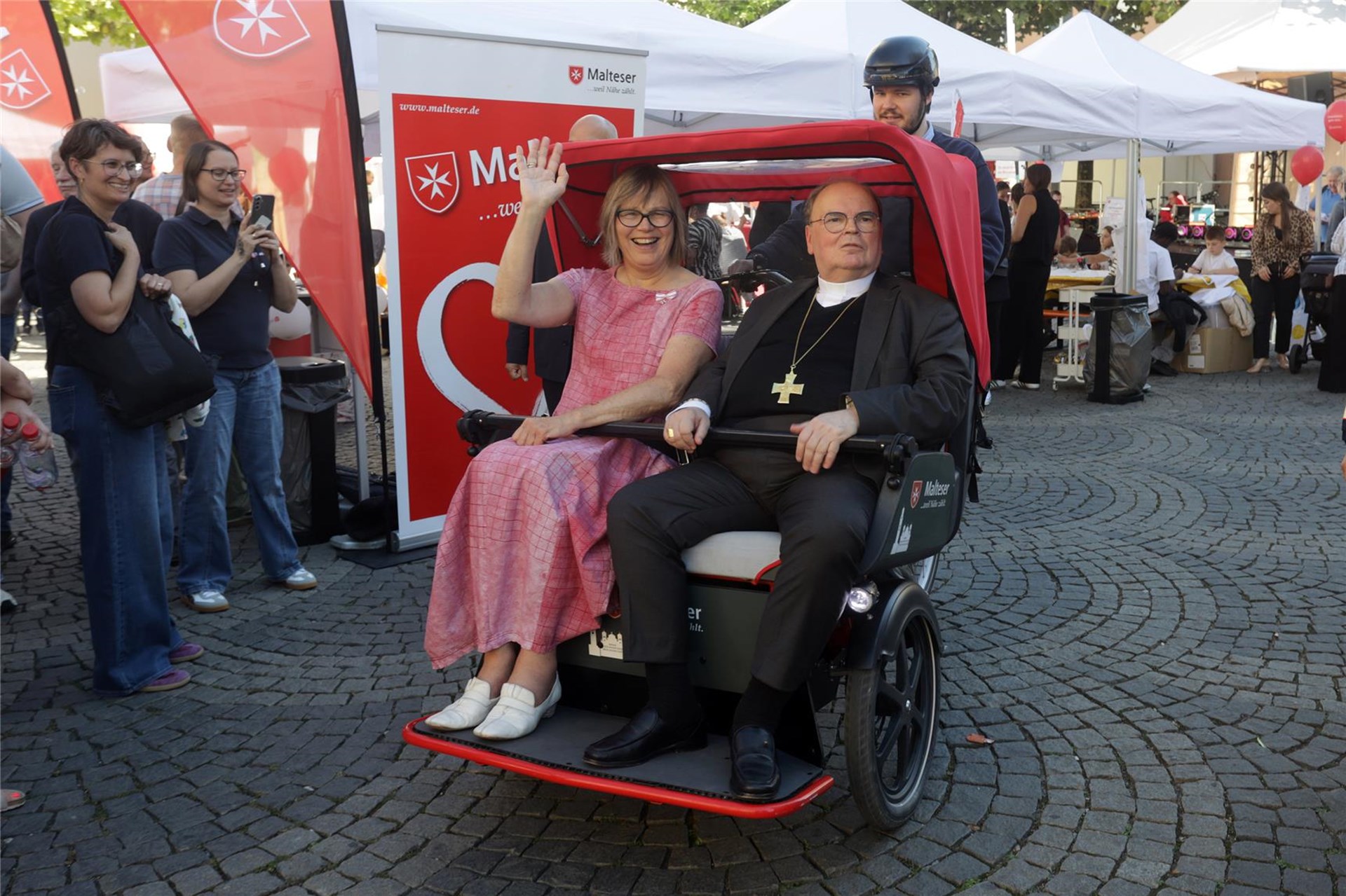 Das Foto zeigt die Präsidentin des Deutschen Caritasverbandes Eva Maria Welskop-Deffaa und den Augsburger Bischof Dr. Bertram Meier. Beide sitzen in einer Rickscha. 